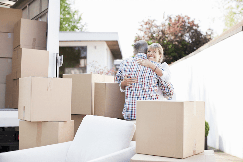 Couple hugging by a moving truck with boxes